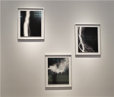 杉本博司“放電場”系列。《筆觸印象·心經(jīng)》之前，藝術(shù)家在暗室中創(chuàng)作“隱形”文本的嘗試早就有跡可循。在2006年開啟的“放電場”系列作品中，杉本博司便已嘗試突破基于鏡頭捕捉的暗室工作方式，用電流導(dǎo)向膠片以獲得圖像。