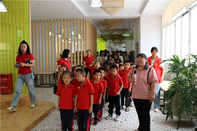 李躍慧拿著話(huà)筒在給進(jìn)圖書(shū)館參觀(guān)的小朋友做講解