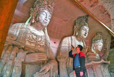 義務(wù)文保員在對(duì)重慶市大足區(qū)寶頂鎮(zhèn)香山社區(qū)的佛祖巖摩崖造像進(jìn)行巡查。新華社記者 王全超攝