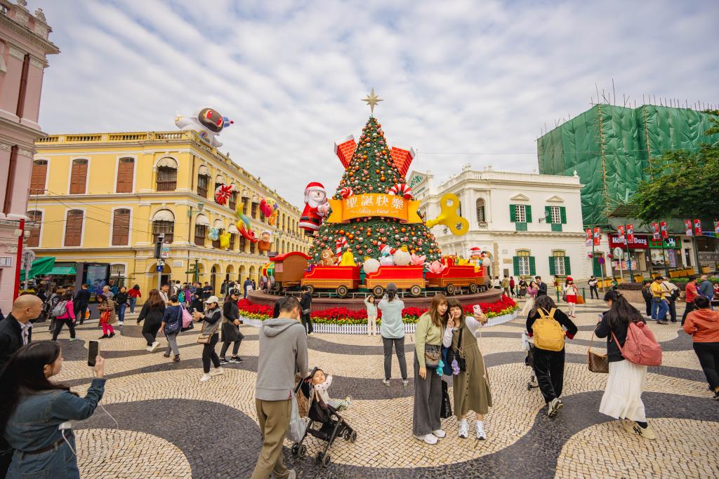 12月12日，游客在澳門(mén)議事亭前地的圣誕樹(shù)前拍照。新華社記者 朱煒 攝