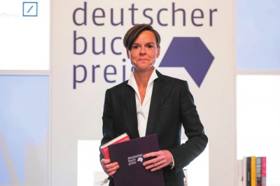 作家安特耶·拉維克·施特魯貝爾在2021年德國(guó)圖書(shū)獎(jiǎng)?lì)C獎(jiǎng)典禮上手持《藍(lán)色女人》和獲獎(jiǎng)證書(shū)。攝影:托馬斯·洛內(nèi)斯